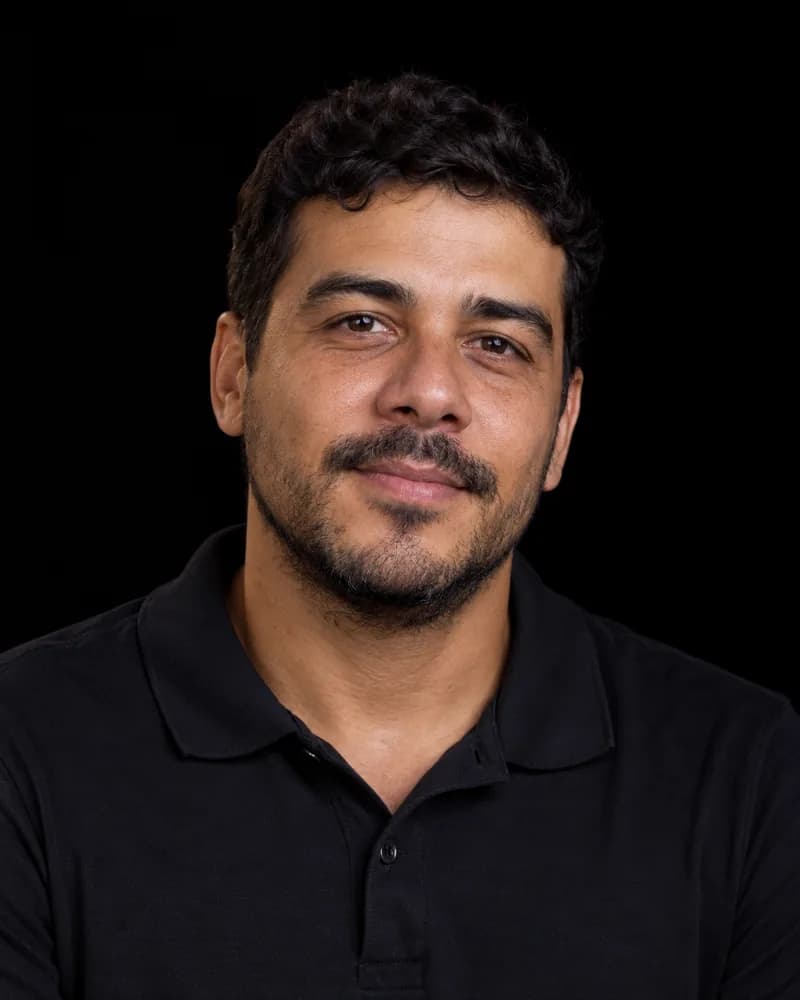 Gustavo Meireles, de camisa polo preta, com um meio sorriso.